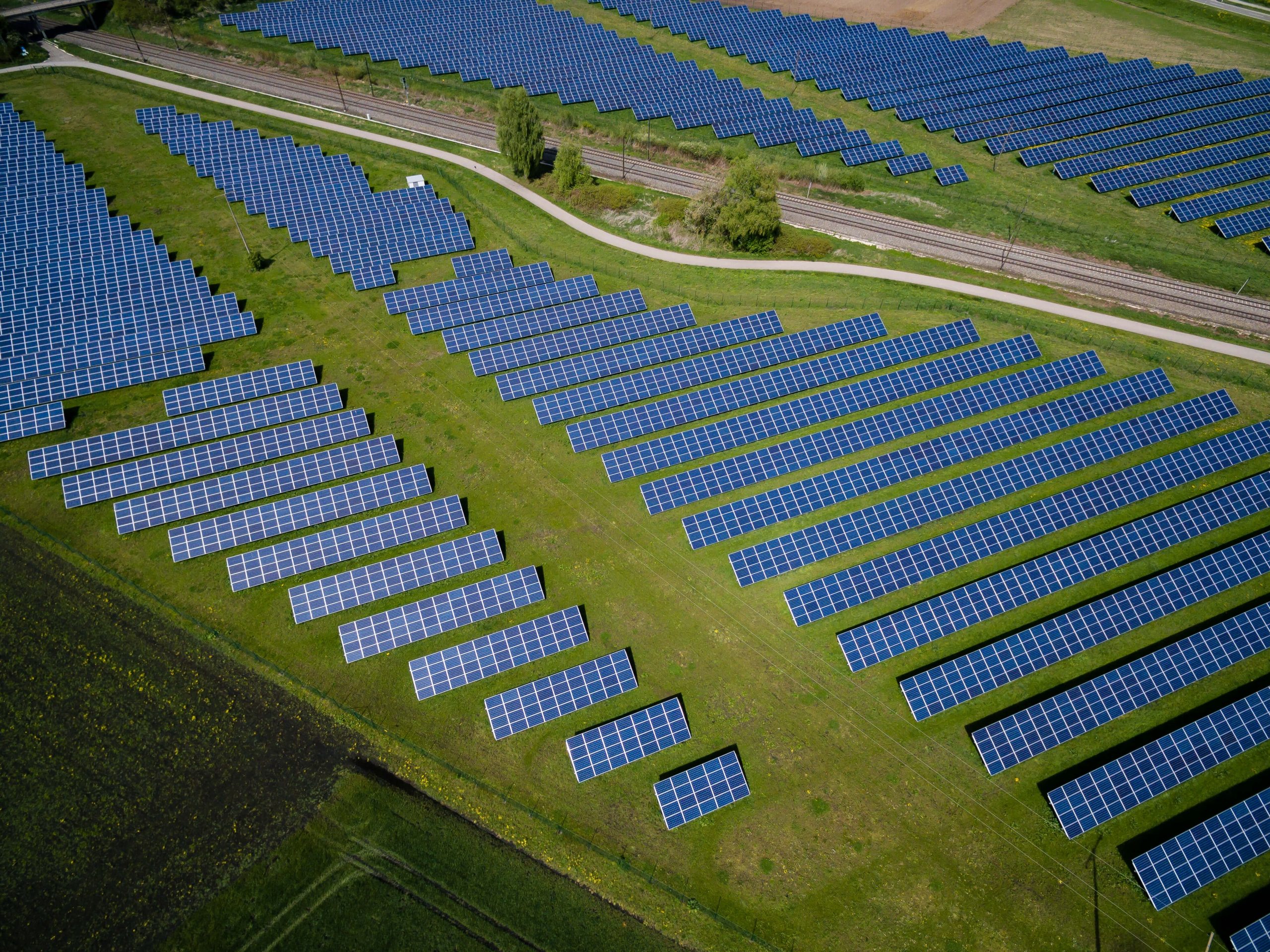 Solar panels laid out on green grass, photographed from above. 